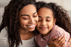 a mother hugs her daughter as she uses a warm parenting style