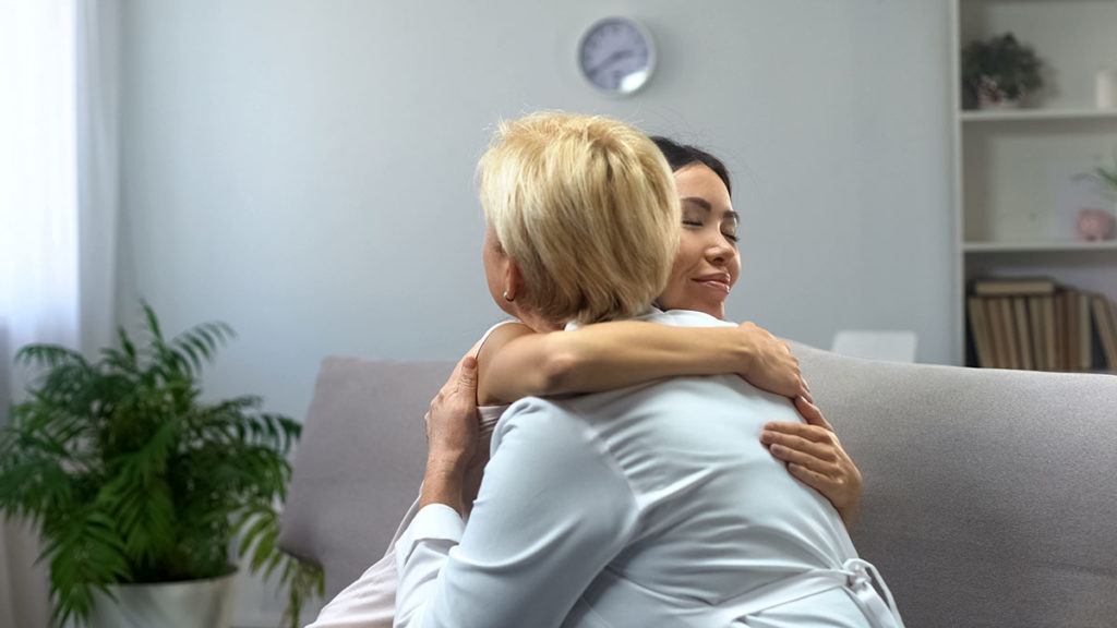 Two women hug each other after talking about getting support for an individual in recovery