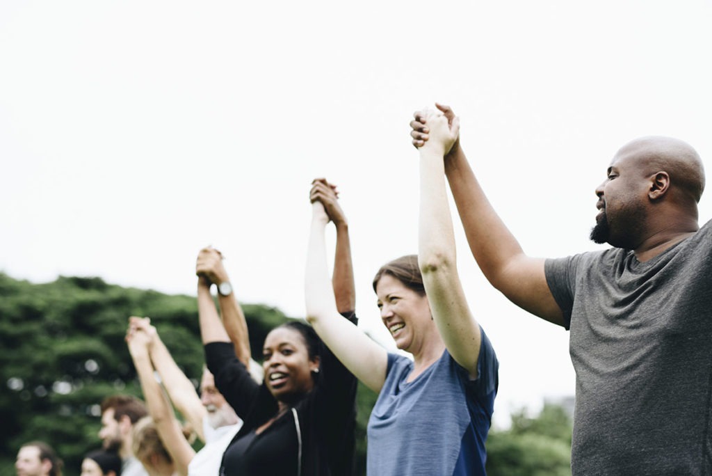 A group of people raise their hands together to celebrate a successful long term recovery