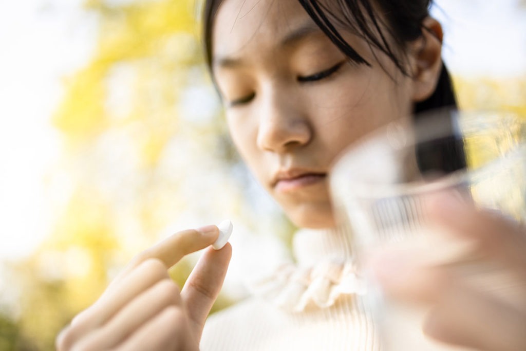 A girl stares at a pill and thinks about teens abusing prescription painkillers