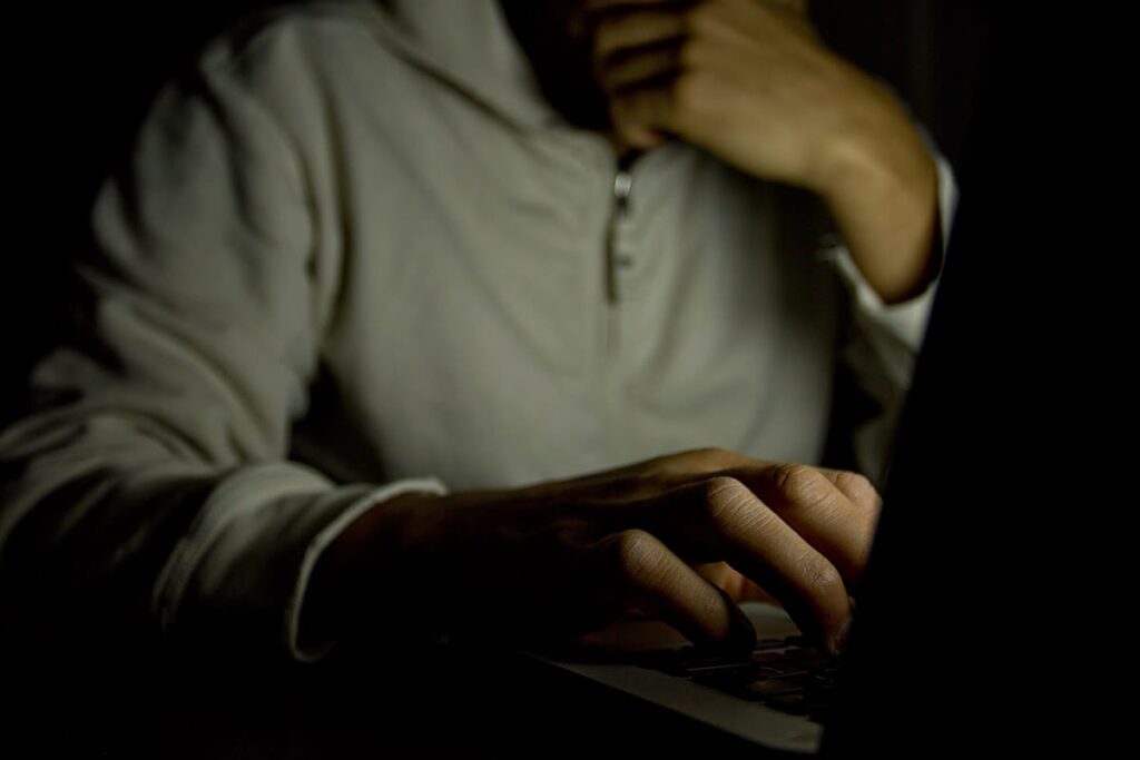a person experiencing a cybersex addiction sits in the dark on a computer