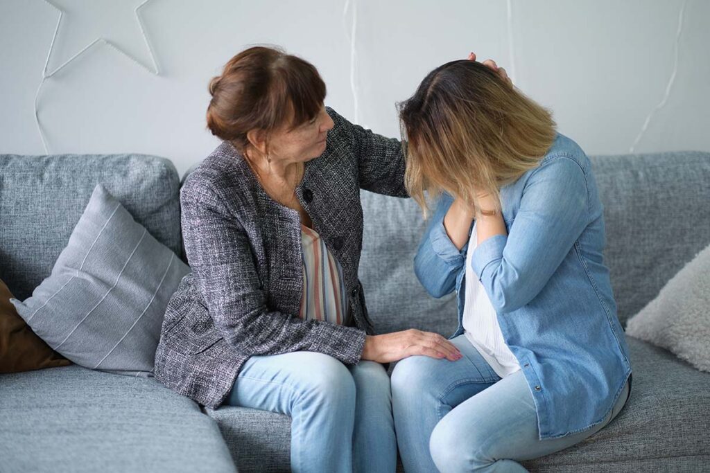 a person comforts another on a couch possibly after admitting they have a cocaine problem