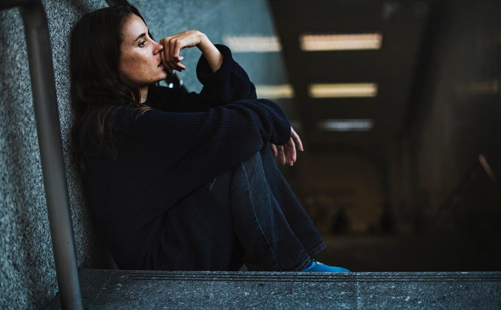 a person sits sadly against a wall possibly struggling with street drugs in texas