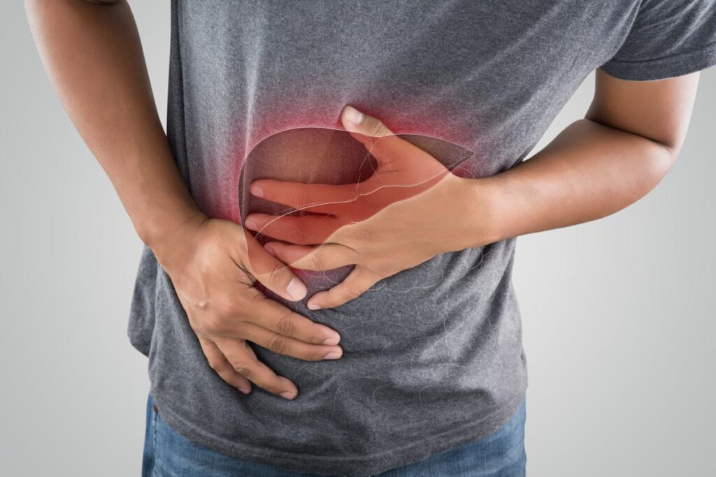 Man clutching at their mid-section, struggling with alcohol and its effect on liver