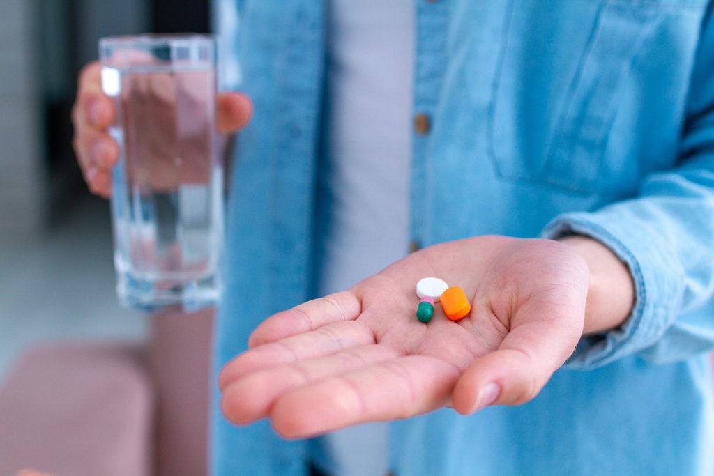 mix of pills in hand to take with water for myths about drugs