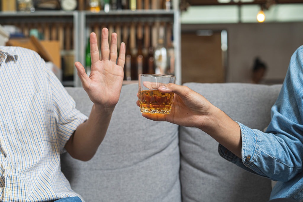 a woman on a couch denying a drink showing how to quit drinking