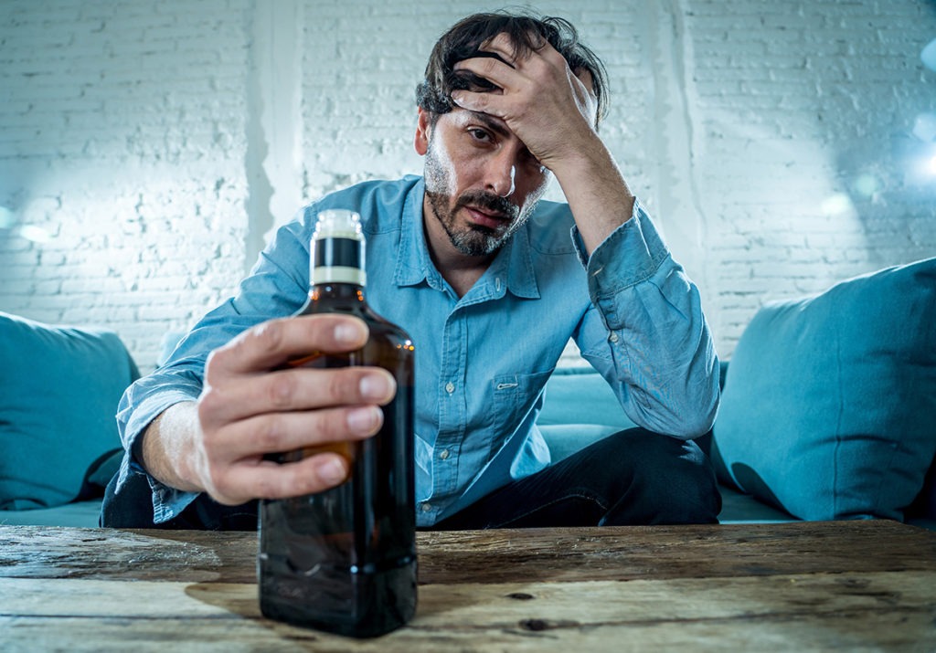 a man with a bottle showing signs of psychological dependence
