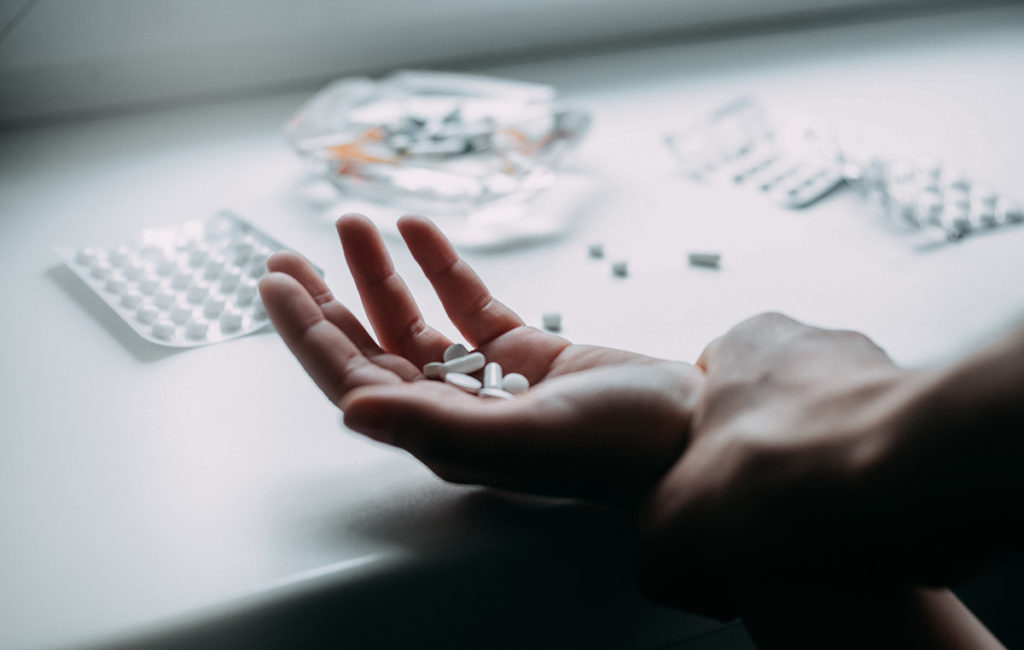 a person holding pills displaying the stages of addiction