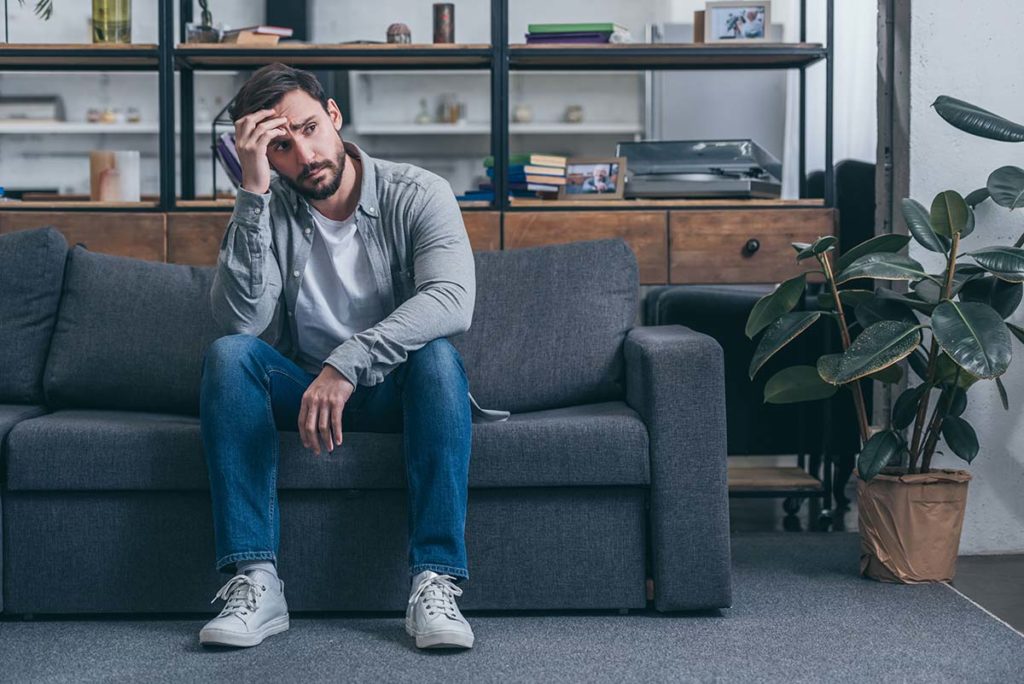 a man puts his hand on his head as he considers 5 causes of binge drinking