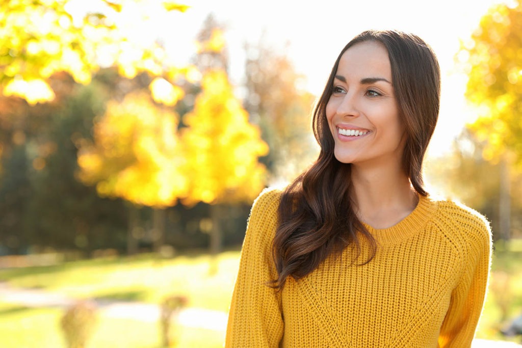 a woman looks off to the side as she thinks about critical components of an effective addiction recovery aftercare program