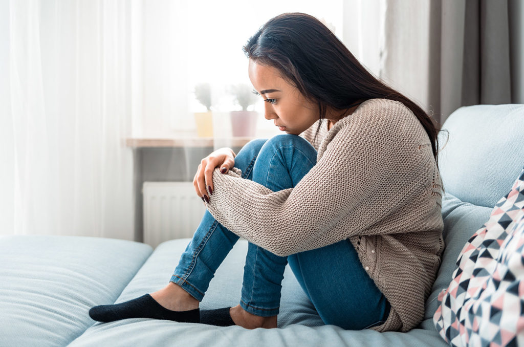 a woman sits on her bed and wonders about the dangers of designer drugs