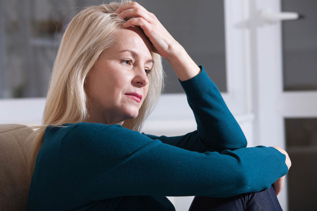 a woman sits on a couch and thinks about how prescription drug use continues to rise