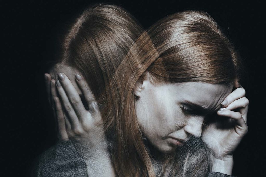 a woman holds her head as she thinks about the role of dopamine and brains reward circuitry in mood disorders