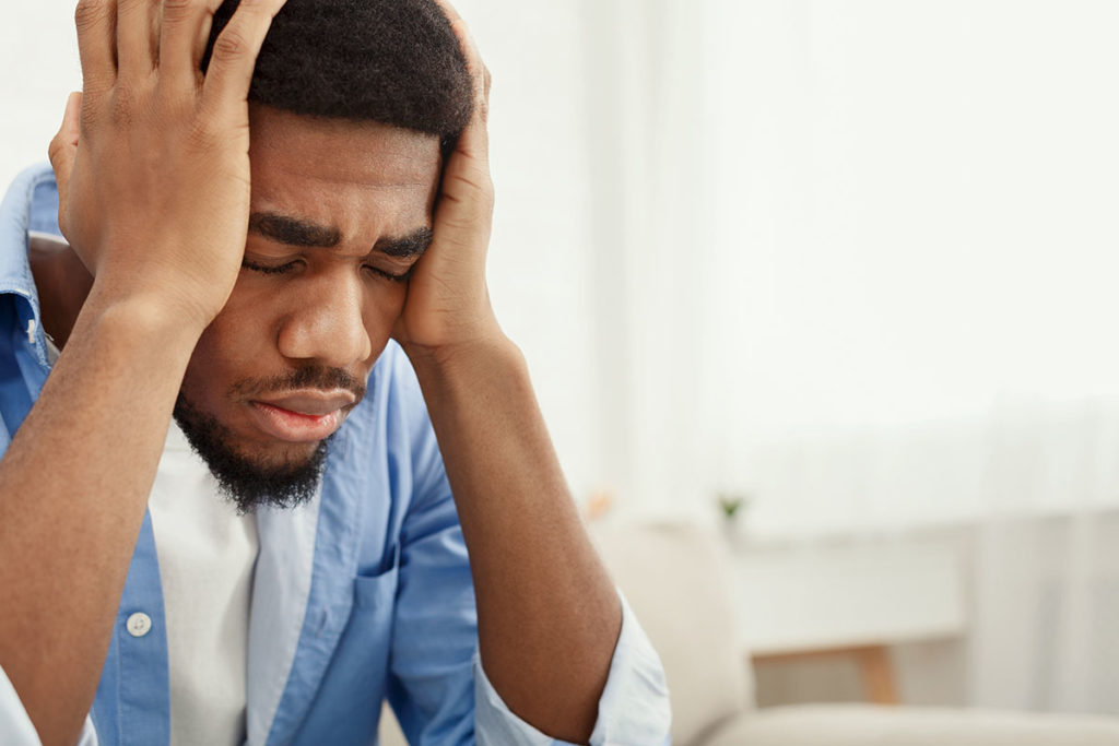 a man holds his head as he thinks about side effects of adderall addiction