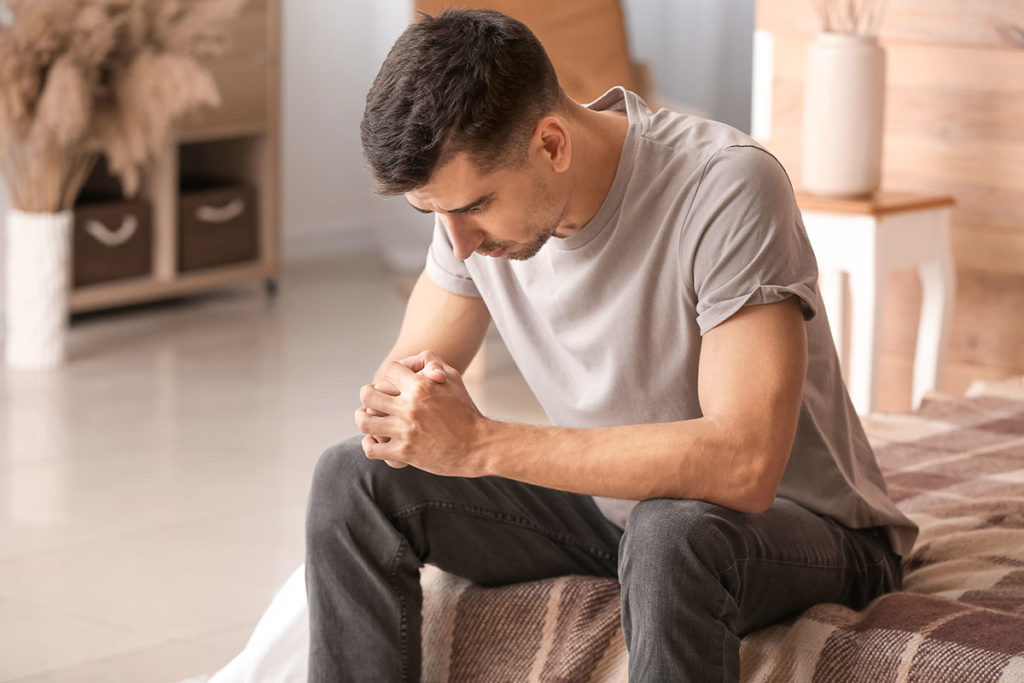 a man sits on his bed and considers depression treatment in covid-19