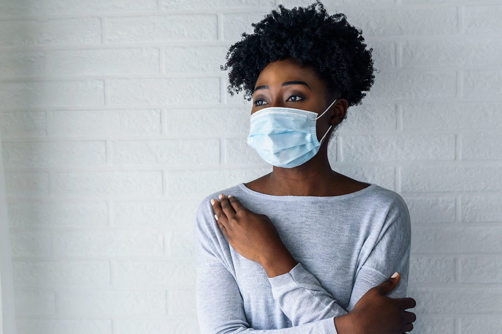 a woman wears a mask and considers an epidemic vs a pandemic
