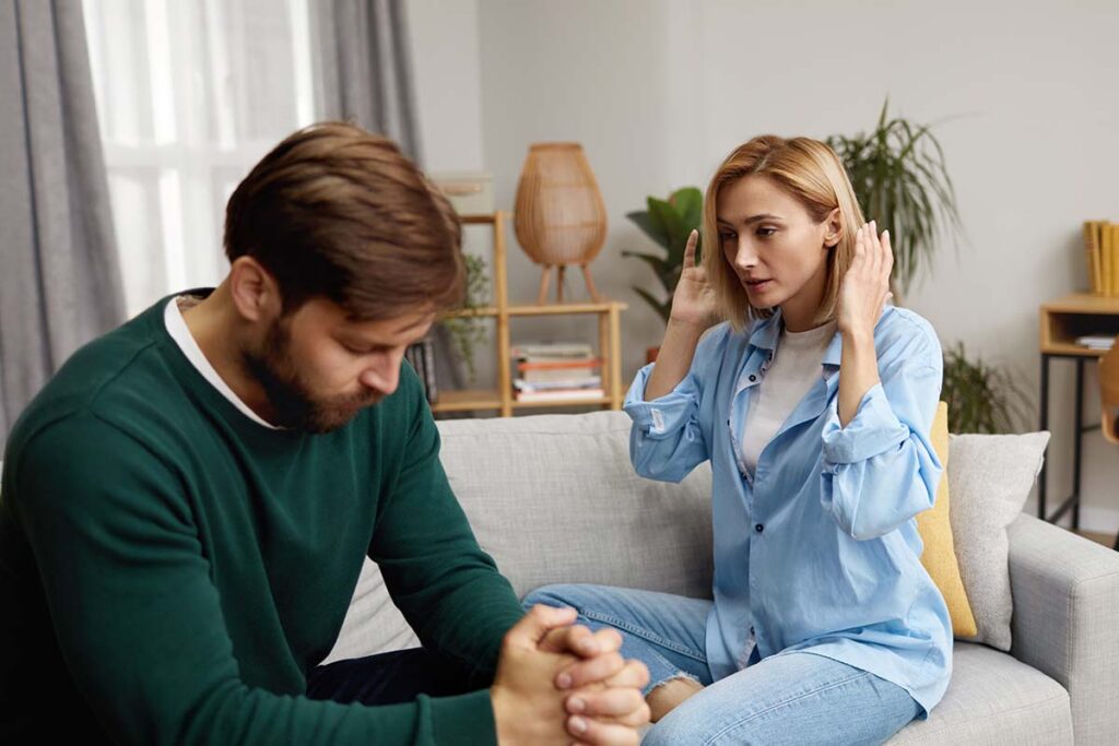 while sitting on a couch two people talk about how to help a violent alcoholic spouse