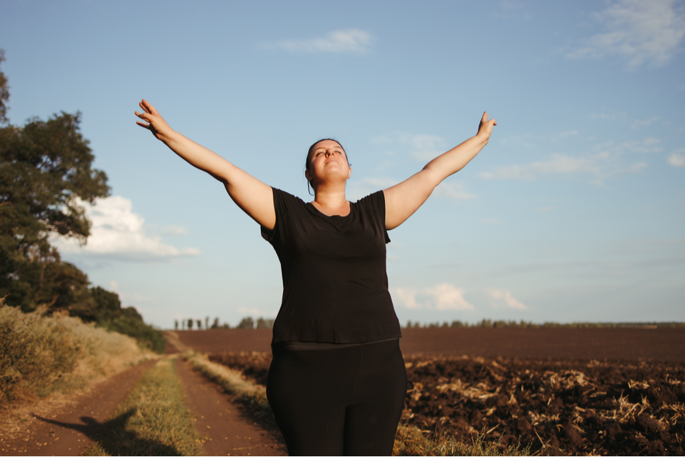Woman outside with arms up, expressing forgiveness in recovery