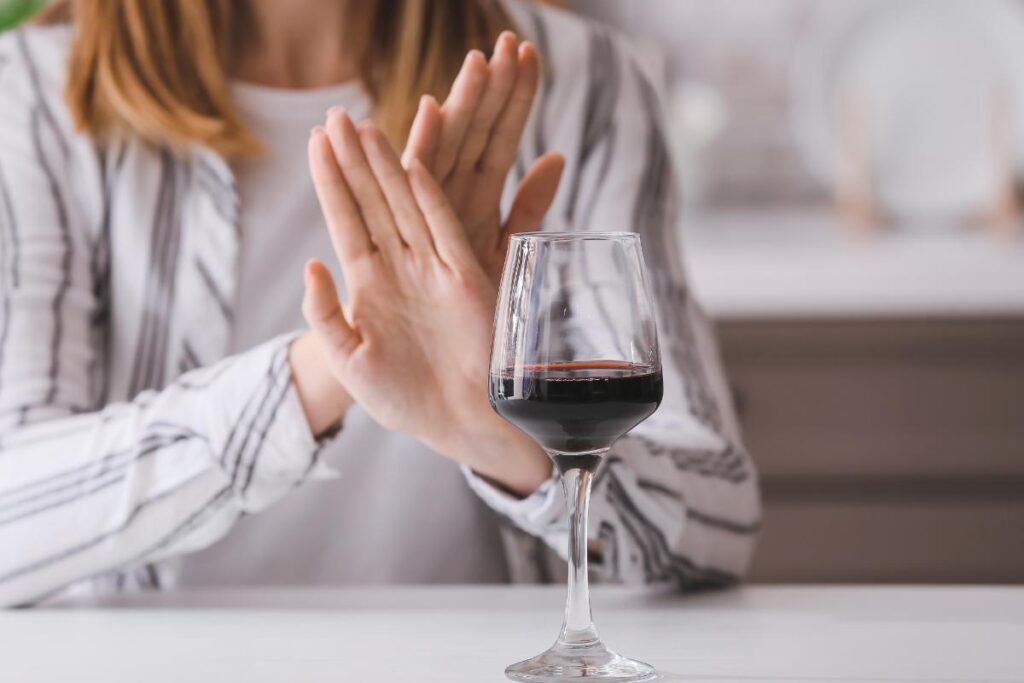 woman saying no to glass of wine and drugs