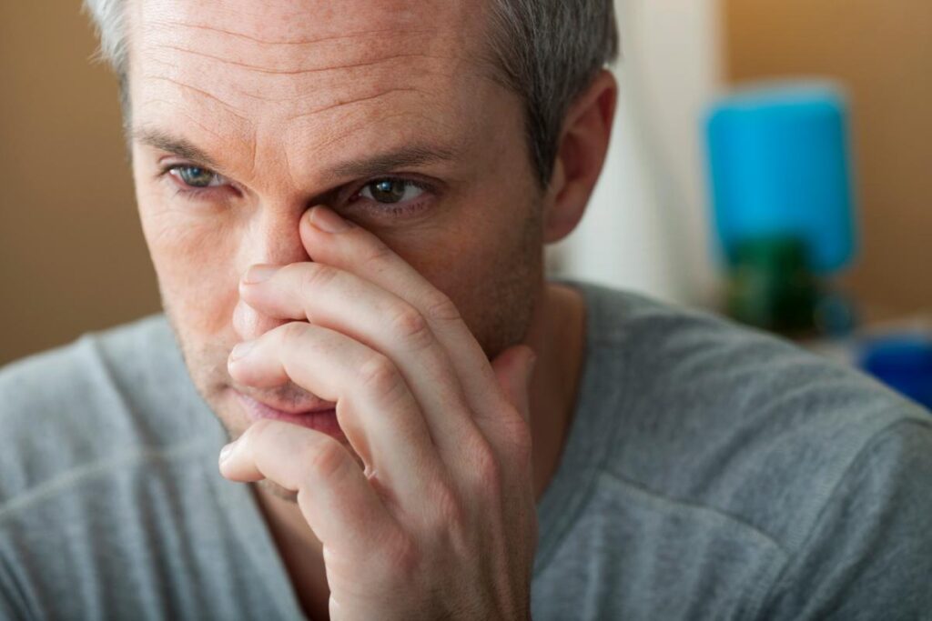 young man touching his nose and looking for signs of nasal damage from snorting heroin