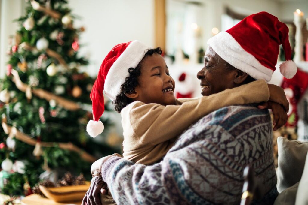 Man and his grandson hugging, wearing Santa hats, enjoying stress-free holiday