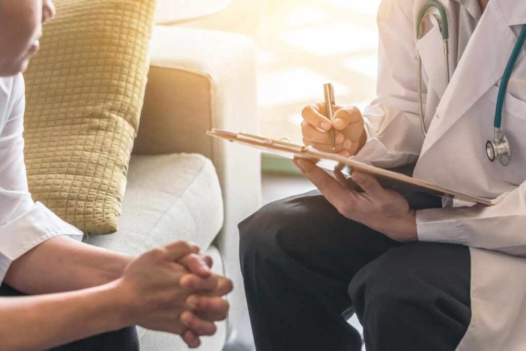 Health professional sitting with patient taking notes in aftercare program