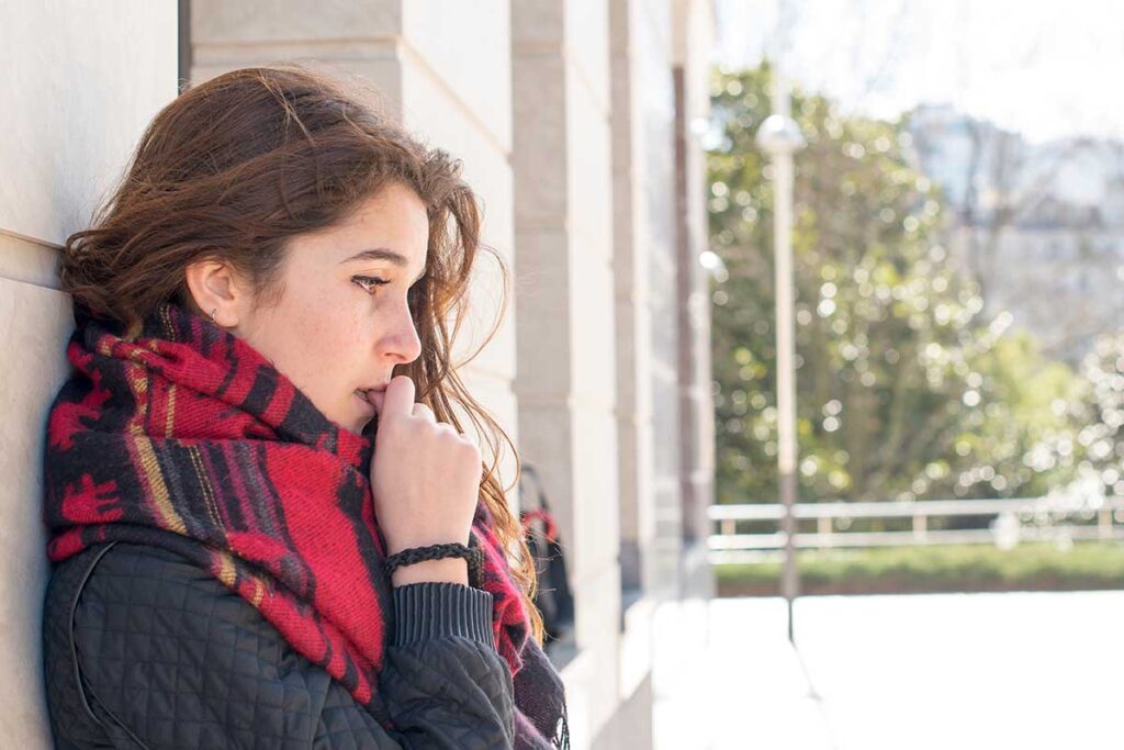 a person stands outside against a marble building wondering why are some people more susceptible to trauma?