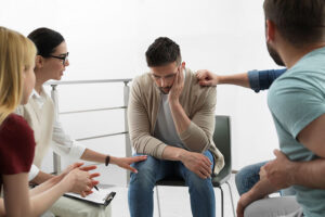 a group of people sitting in a circle in a Drug Rehab Program comfort each other