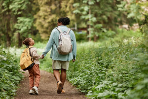 an adult and a child hold hands and walk down a trail to represent Sober Living