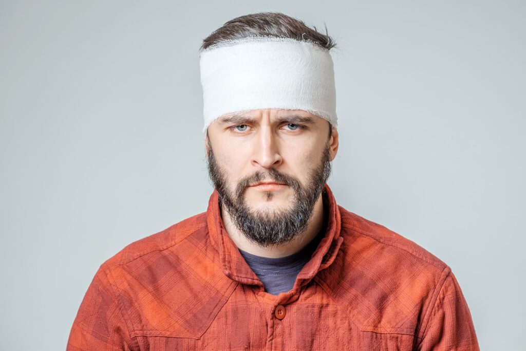 Man with bandage around his concussed head wonders, "can you drink if you have a concussion?"
