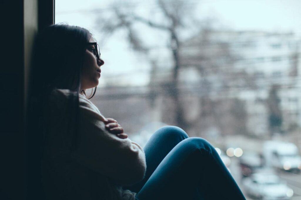 Woman leans on window as she thinks about the dangers of using opioids during winter