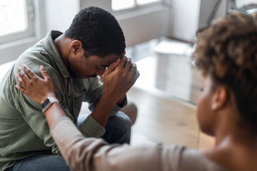 Woman puts arm on man who is showing signs of 2C-B addiction