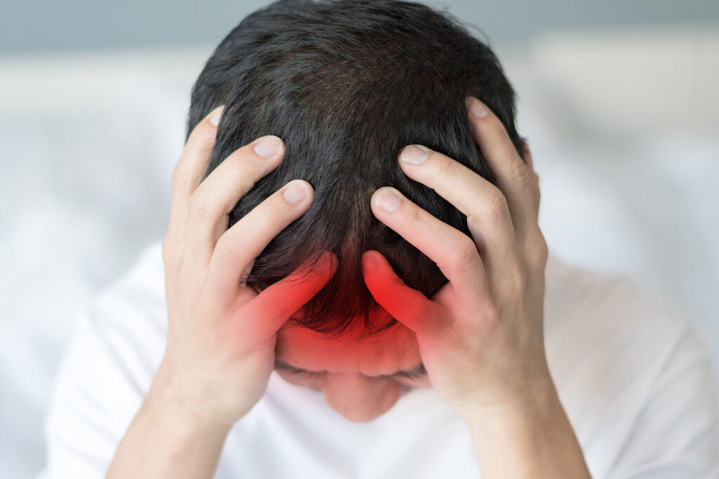 Man rubs his head while wondering, "can you drink with post-concussion syndrome?"