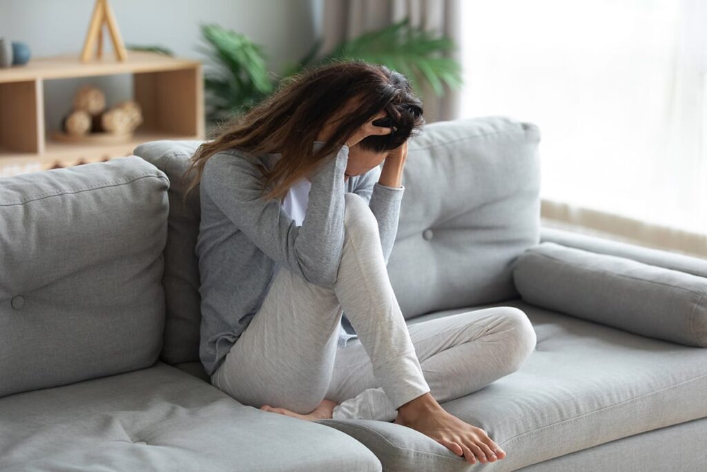 Woman curls up on couch and wonders, "does THC cause anxiety?"
