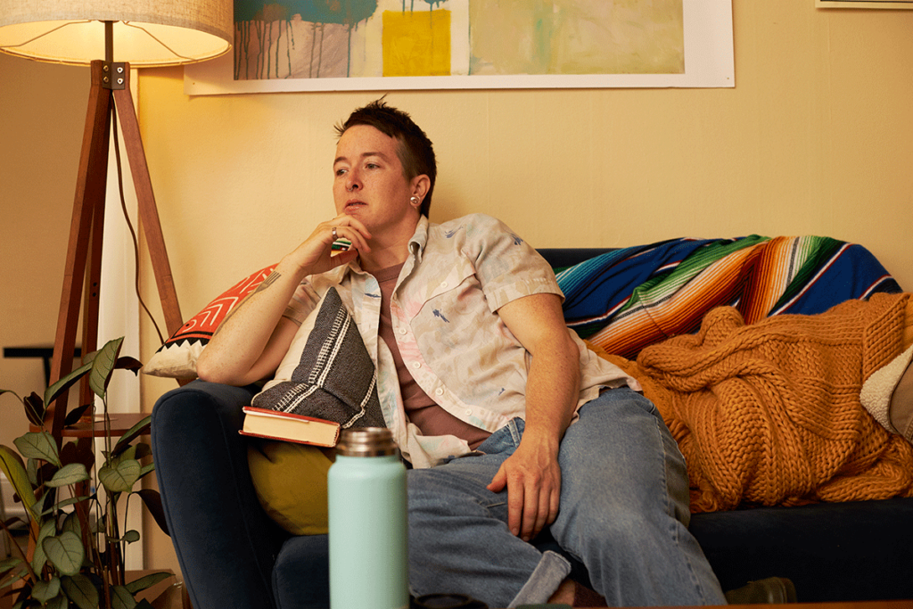 Person sits on couch and ponders what makes people crave alcohol