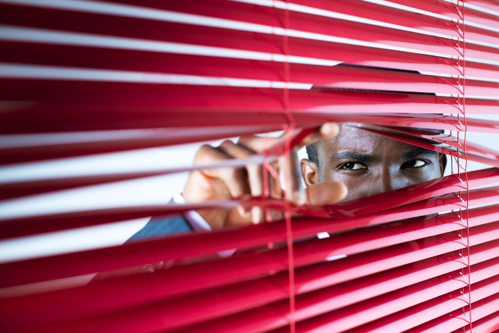 Person looking out through Venetian blinds, thinking about what Adderall paranoia is