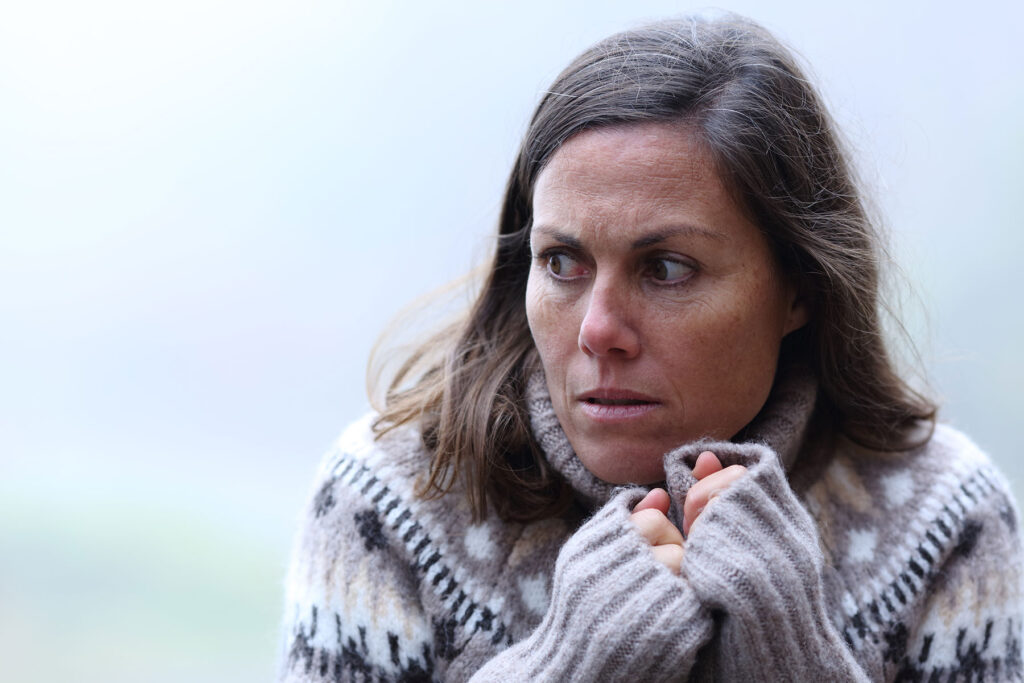 Woman hides in her sweater while wondering which characteristics are a sign of drug addiction?