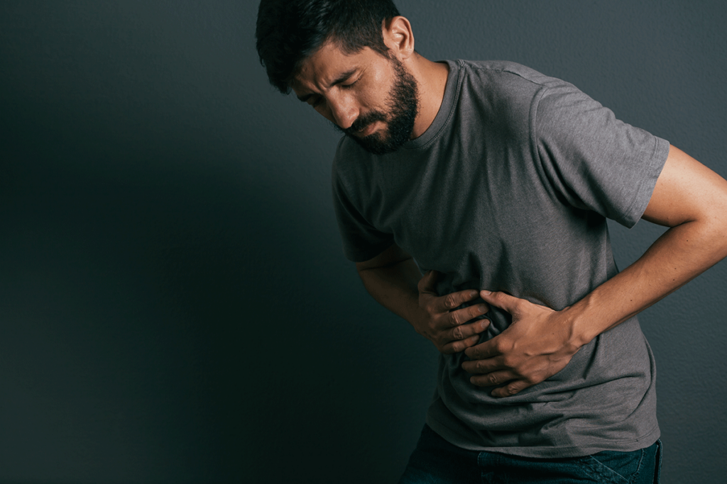 Man grabs at his stomach, wondering, "how long does it take an alcoholic to detox"