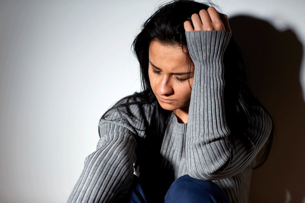 Woman sits on the floor in agony, wondering what the difference between alcohol abuse and alcohol dependence is